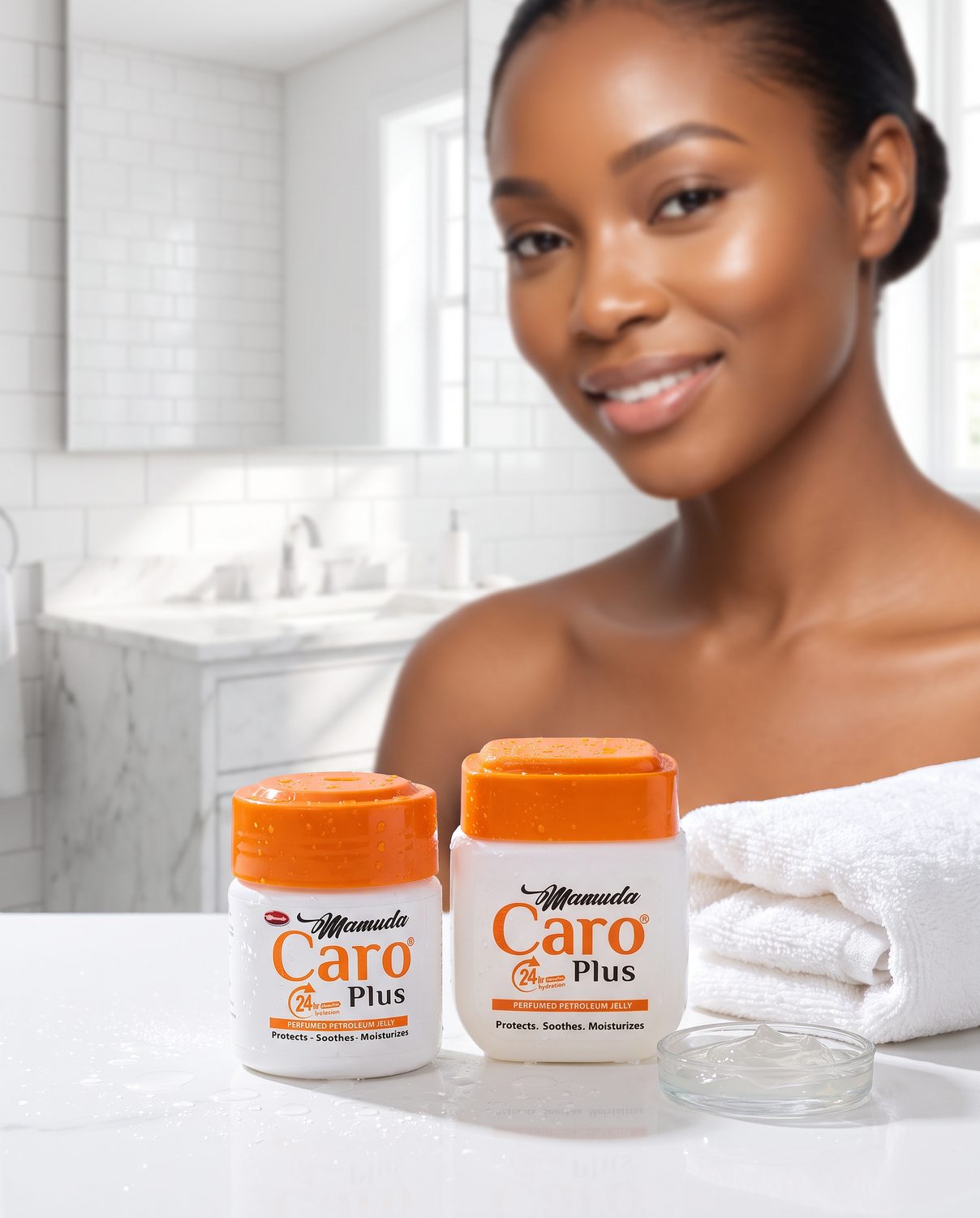 A Nigerian woman with healthy, softly glowing skin in a bright white bathroom, with the white and orange Mamuda Caro Plus petroleum jelly jars large in the foreground beside a folded white towel