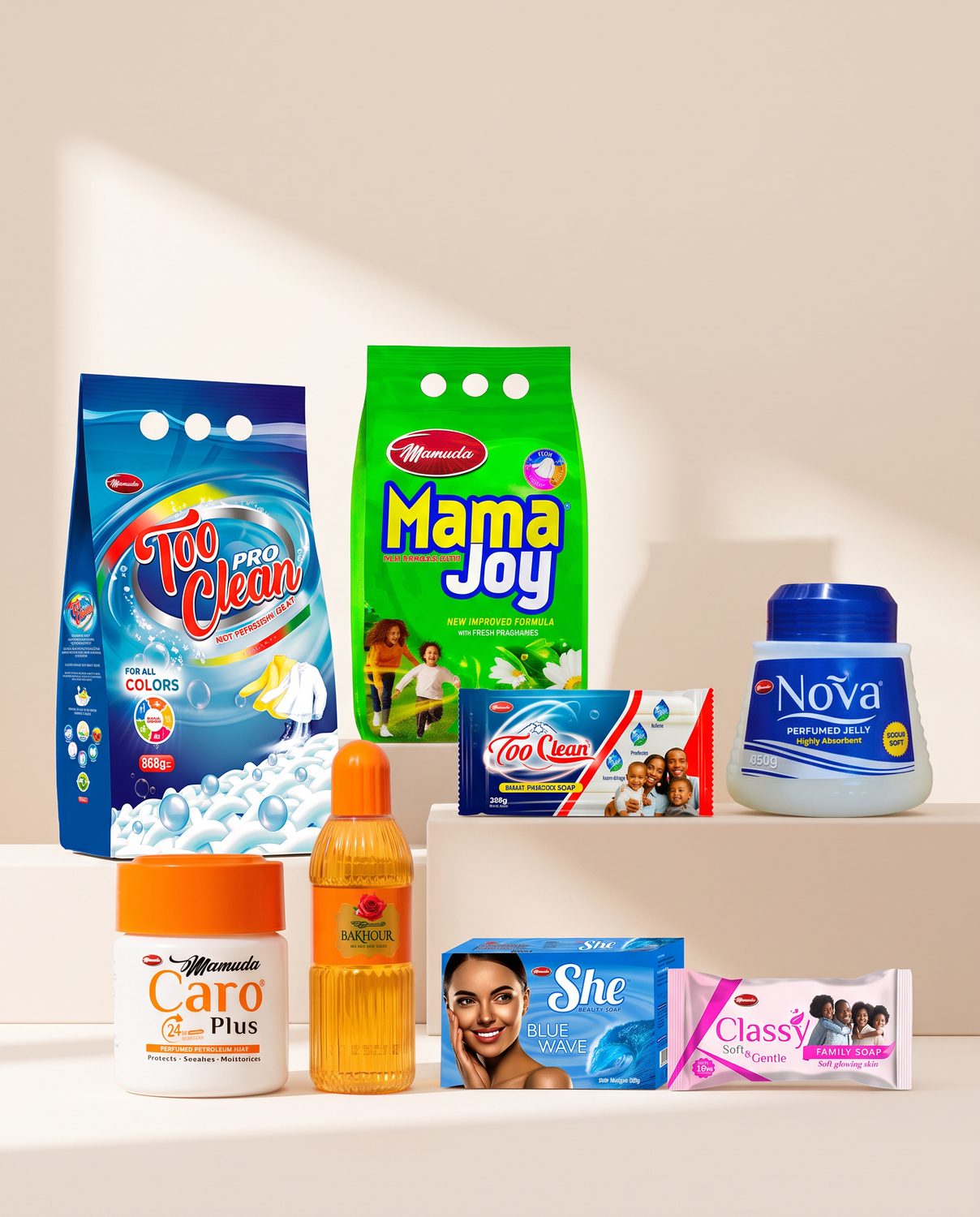 The full Mamuda Care range assembled on a marble surface: Too Clean Pro and Mama Joy detergent packs behind, with Nova and She beauty soap cartons, a Classy family soap bar, a Too Clean Multipurpose bar and a Mamuda Laundry Soap bar in front